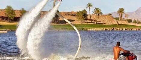 A person wakeboarding over water with a wakeboard and a wakeboarder in a boat.
