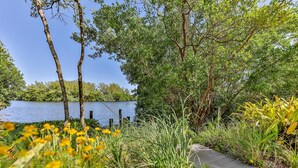 A pathway leading to a lake surrounded by lush greenery and trees. - LAKE PALMS 7 - Newly Updated Sanibel Condo Overlooking Lagoon (Sanibel)