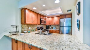 A kitchen with wooden cabinets, granite countertops, stainless steel appliances, and a skylight. - LAKE PALMS 7 - Newly Updated Sanibel Condo Overlooking Lagoon (Sanibel)