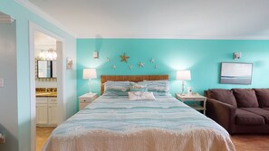 A bedroom with a bed, nightstands, a lamp, a starfish decoration, and a painting on the wall. - Studio Condo in Town, Near Beach, Shared Pool and Hot Tub (Port Aransas)