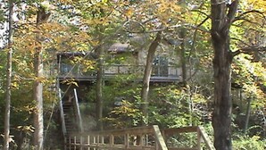 A wooden bridge in a forested area with a view of a building in the background. - Riverfront - main level master bedroom - now with high speed unlimited Internet! (Bowden)