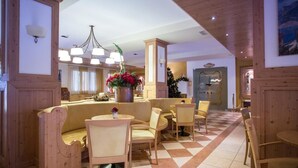 A lobby with a checkered floor, wooden furniture, and a Christmas tree. - Park Hotel Sacro Cuore (Cavalese)