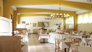 A dining area with multiple tables and chairs, a chandelier, and artwork on the walls. - Park Hotel Sacro Cuore (Cavalese)