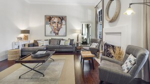 A modern living room with a grey sofa, a coffee table, and a patterned rug. - Beautiful Cottage with Private Pool & Large Screened porch in Village Area (St Simons Island)