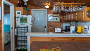 A compact kitchen with wooden cabinets, a refrigerator, a microwave, a toaster, and a coffee maker. - Lucky Catch: Best Cottage on the Best Lake! (Penn Yan)