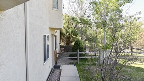 Una casa amb un camí de formigó que condueix a una tanca de fusta i un arbre petit.