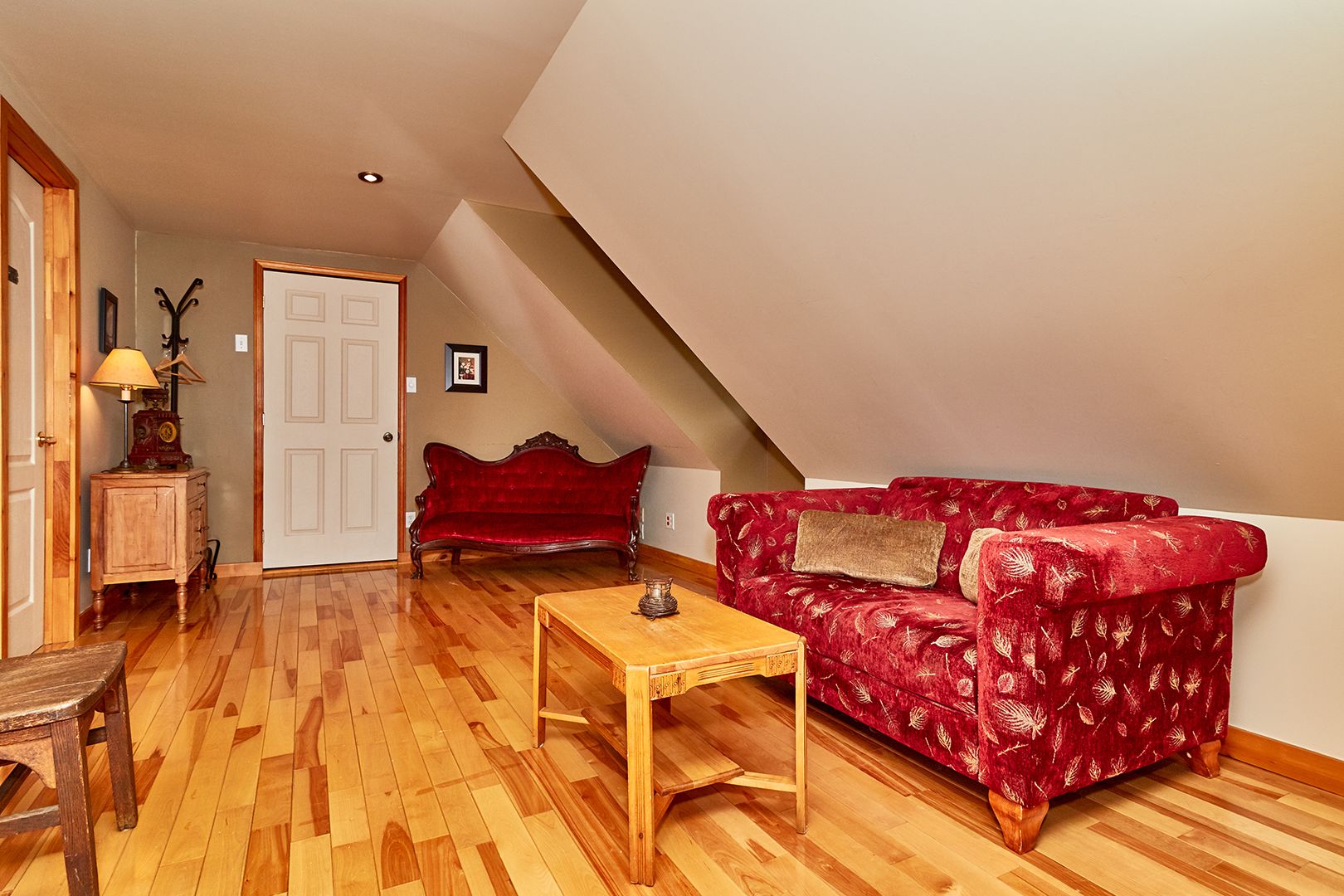 Una sala de estar acogedora con un sofá rojo, una mesa de centro de madera y un armario de madera.