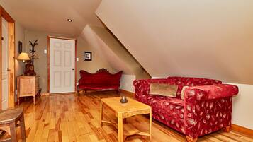 Una sala de estar acogedora con un sofá rojo, una mesa de centro de madera y un armario de madera.
