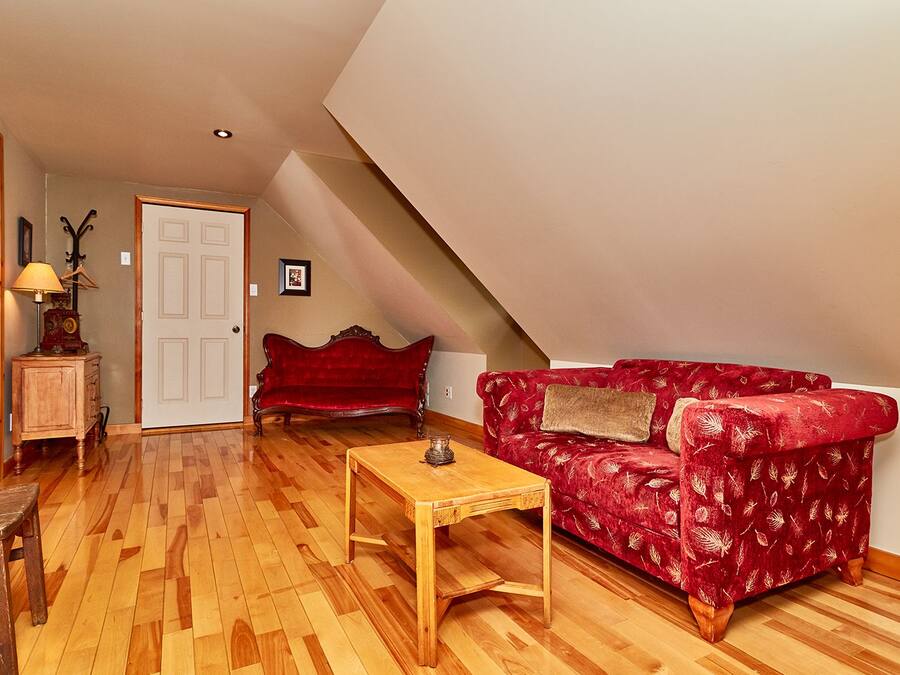 Una sala de estar acogedora con un sofá rojo, una mesa de centro de madera y un armario de madera.