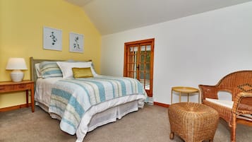 A bedroom with a bed, a nightstand, a lamp, a chair, and a window.