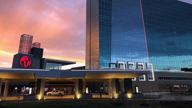 A modern hotel with a prominent glass facade and a distinctive logo on the building. - Resorts World Catskills Casino (Monticello)