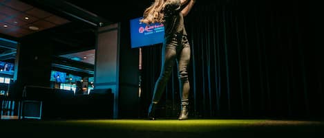 A person on a stage with a microphone, a sign reading "Casino Resort", and a dark interior with visible seating areas.