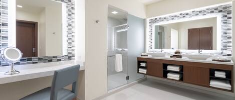 A modern bathroom with a large mirror, a vanity with a sink, and a shower area.