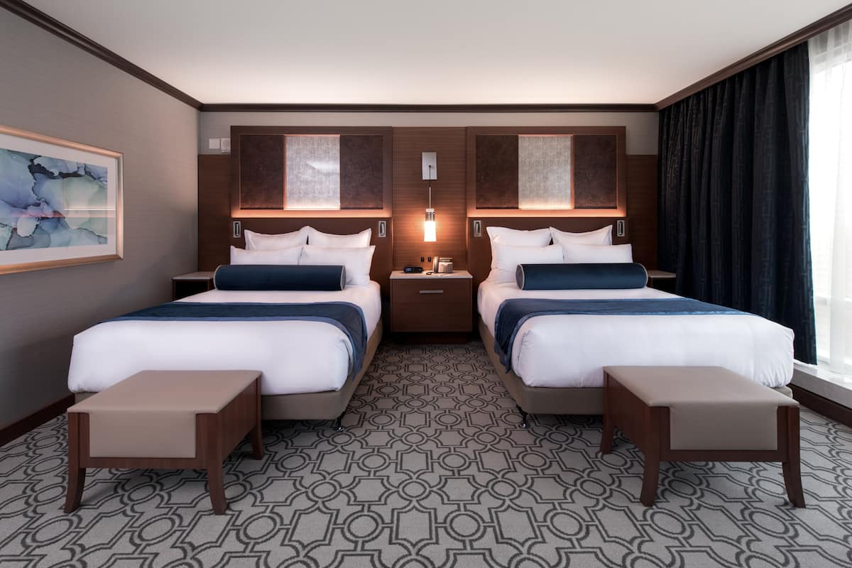 Une chambre d’hôtel avec deux lits, une table de chevet, une lampe et un tableau au mur.