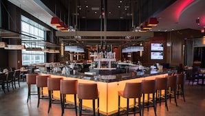 A modern bar area with a central island, bar stools, and overhead lighting. - Resorts World Catskills Casino (Monticello)