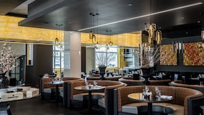 A modern restaurant interior with round tables and booths, pendant lighting, and a view of the street through large windows. - Resorts World Catskills Casino (Monticello)
