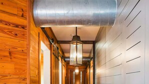 A hallway with wooden floors and walls, a metal duct on the ceiling, and a hanging light fixture. - 2BR Historic Suite Perfect Location Downtown Charleston (Charleston)
