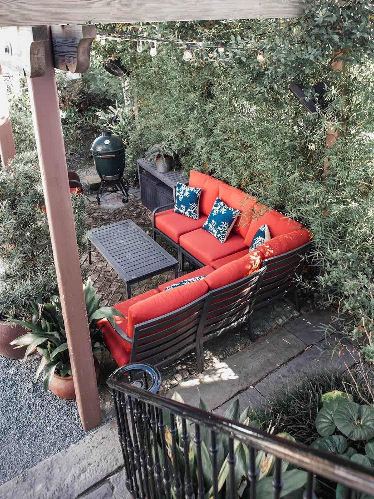 An outdoor patio with a red sofa, two black tables, and a grill.