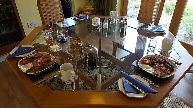 A dining table with various breakfast items, including eggs, toast, and beverages. - A. B&B - Glastonbury (Glastonbury)