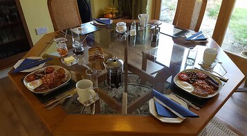 Una mesa de comedor con diferentes alimentos para el desayuno, como huevos, tostadas y bebidas.
