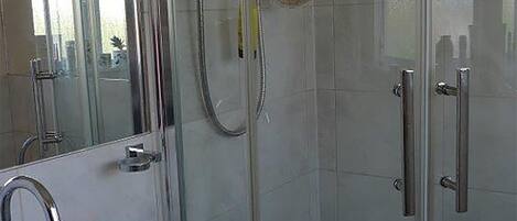 A modern bathroom with a glass shower enclosure, a white sink with a soap dish, and a mirror above the sink.
