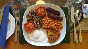 A plate of breakfast food including eggs, mushrooms, tomatoes, beans, sausages, and hash browns on a green placemat. - A. B&B - Glastonbury (Glastonbury)