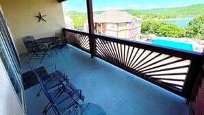 Ein Balkon mit Tisch und Stühlen, einem Deckenventilator und Blick auf einen See und Gebäude.