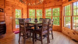 A wooden cabin interior with a dining table, chairs, and a chandelier. - Luxury Cabin, Casino, Ski, Snow Tube, Golf, Hike, Fish, Hot Tub, Fire Pit, Train (Whittier)
