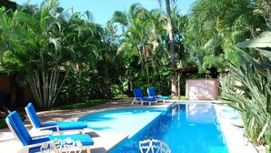 Ein Swimmingpool mit blauem Wasser, umgeben von Palmen und blauen Liegestühlen.