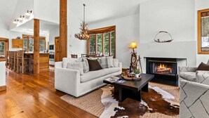 A spacious living room with a fireplace, wooden flooring, and a large window. - RMR: Tram Tower 4 Condo in Teton Village (Teton Village)