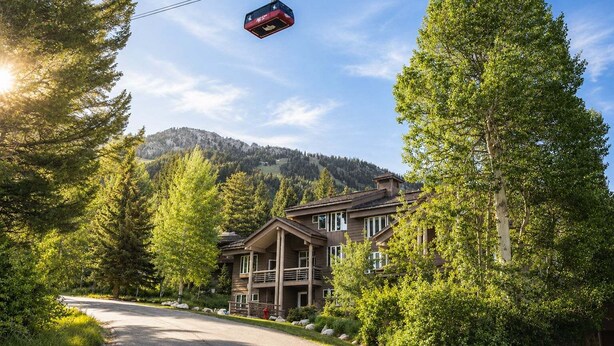 A lodge with a cable car, surrounded by trees and mountains. - RMR: Tram Tower 4 Condo in Teton Village (Teton Village)