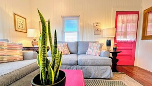 Un salon avec un canapé gris, une table basse noire et une plante en pot.