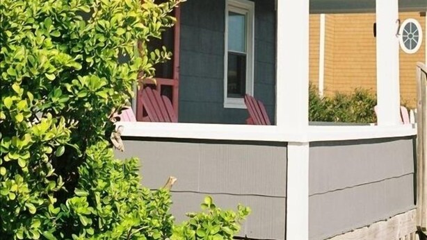 Une maison à deux étages avec un porche couvert, une fenêtre visible et une porte.