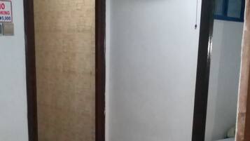 Una habitación con cama, aire acondicionado, ventilador de pared y una puerta.