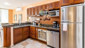 Una cucina con mobili in legno, un frigorifero in acciaio inossidabile, un forno a microonde, un forno e una lavastoviglie.