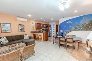 Large common area with dining table for six, flat-screen TV, and beautiful ocean mural