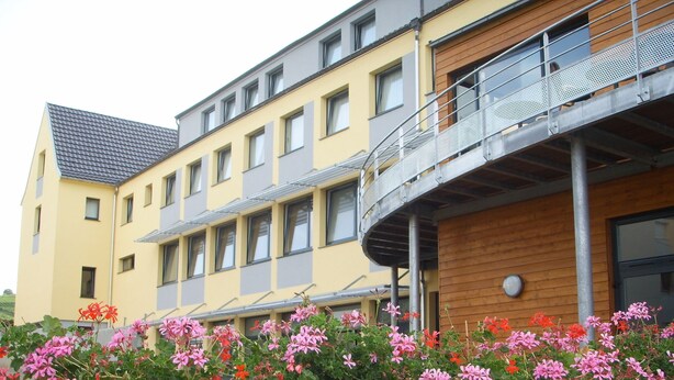 Un edificio de varios pisos con balcones y una pared cubierta de flores.