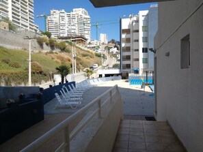 A balcony with sun loungers and a view of a hillside with buildings and a construction crane. - Departamento Euromarina (Vina del Mar)