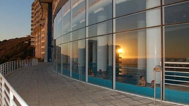 A modern building with a glass facade overlooking a pool area. - Departamento Euromarina (Vina del Mar)