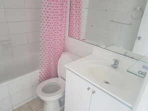 A bathroom with a toilet, a sink, and a shower area. - Departamento Euromarina (Vina del Mar)