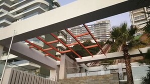 A modern building entrance with a stone wall and a metal gate. - Departamento Euromarina (Vina del Mar)