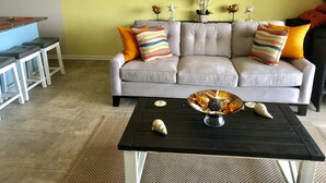 A living room with a grey sofa, colorful striped pillows, a black coffee table with seashells, and a framed seahorse artwork on the wall. - Mayo Clinic under 15 min (6 miles), Beach under 2 min walk (Jacksonville Beach)