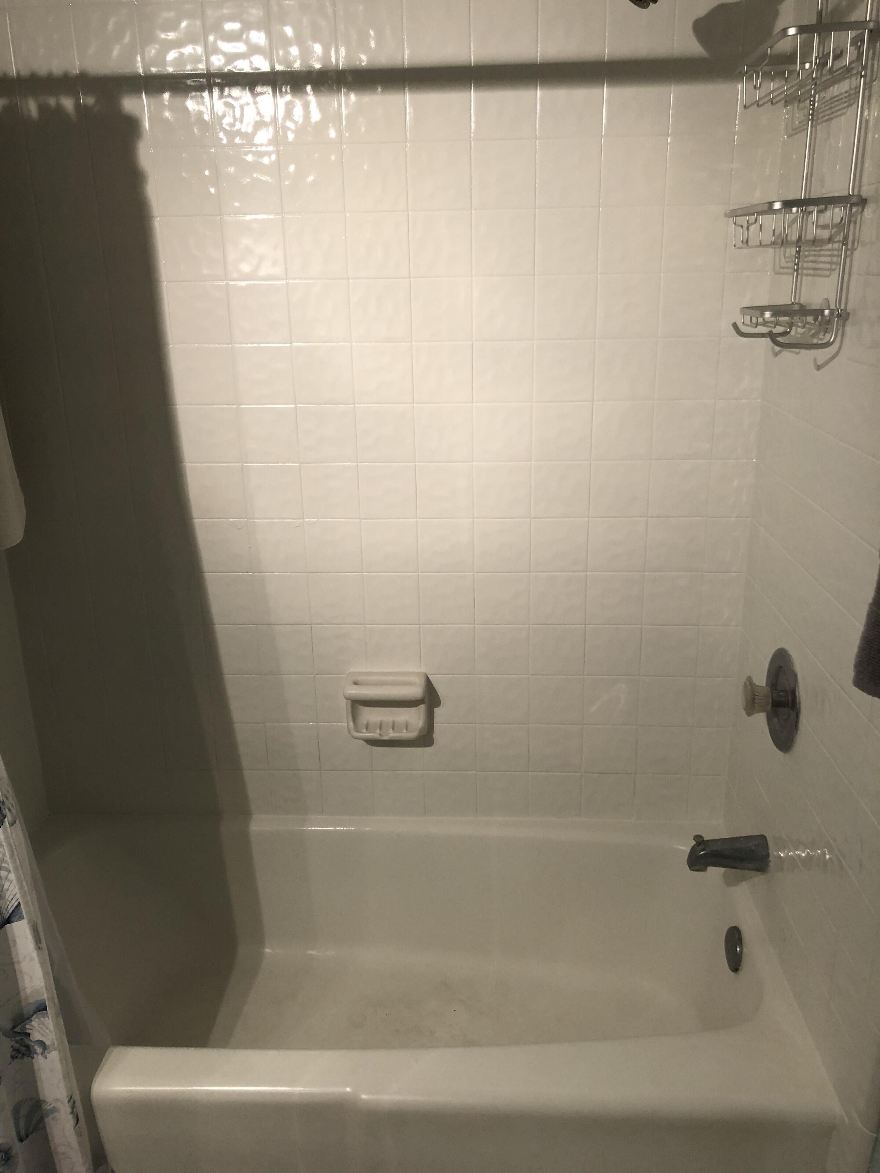 A bathroom with a bathtub, a towel rack, and a soap dish.