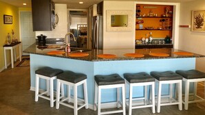 A kitchen with a central island, white bar stools, and decorative wall art. - Mayo Clinic under 15 min (6 miles), Beach under 2 min walk (Jacksonville Beach)