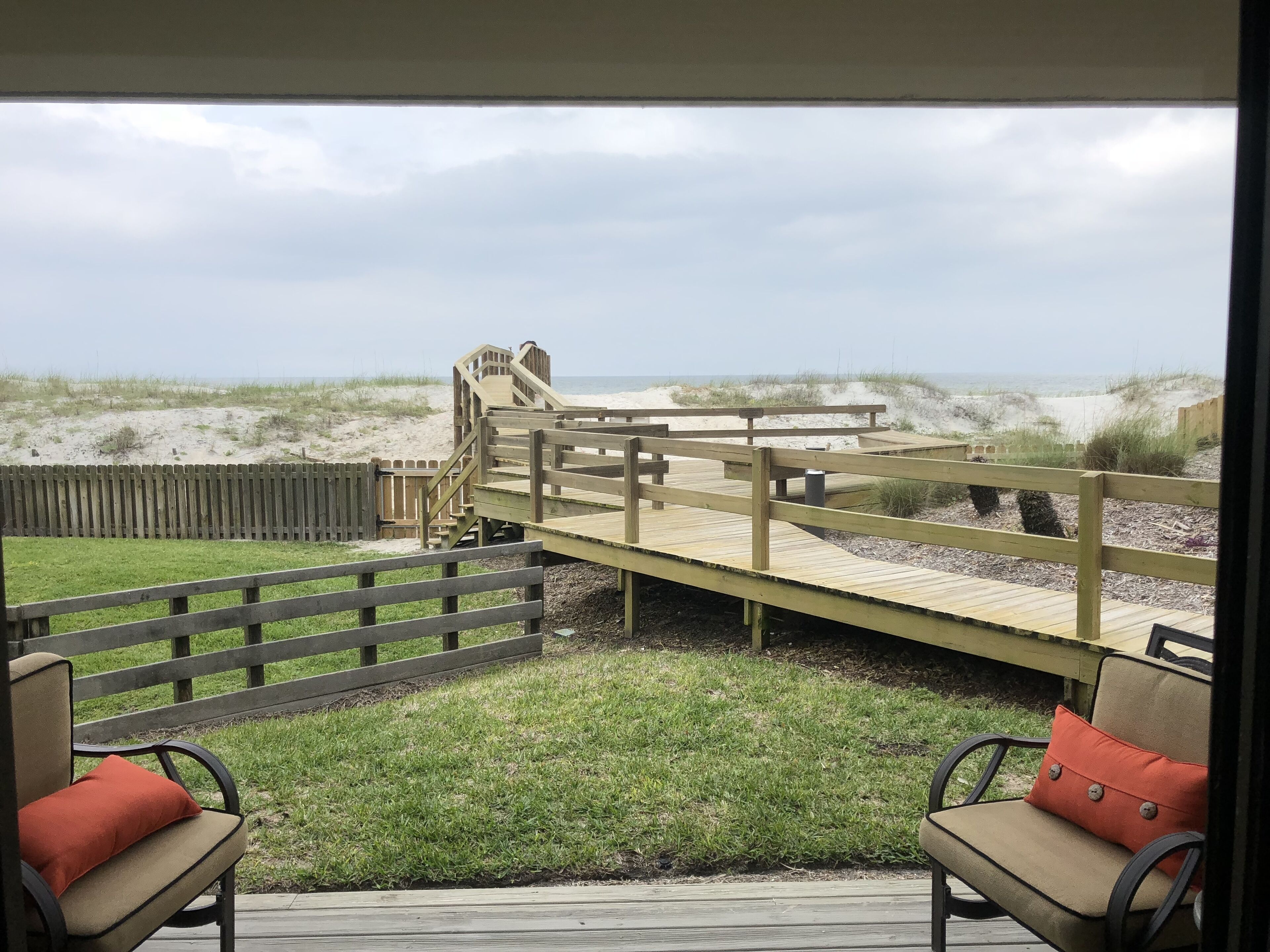 Una terraza de madera con vista a la playa y las dunas.