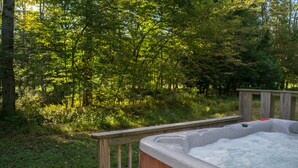 A hot tub in a wooded area with a wooden deck.