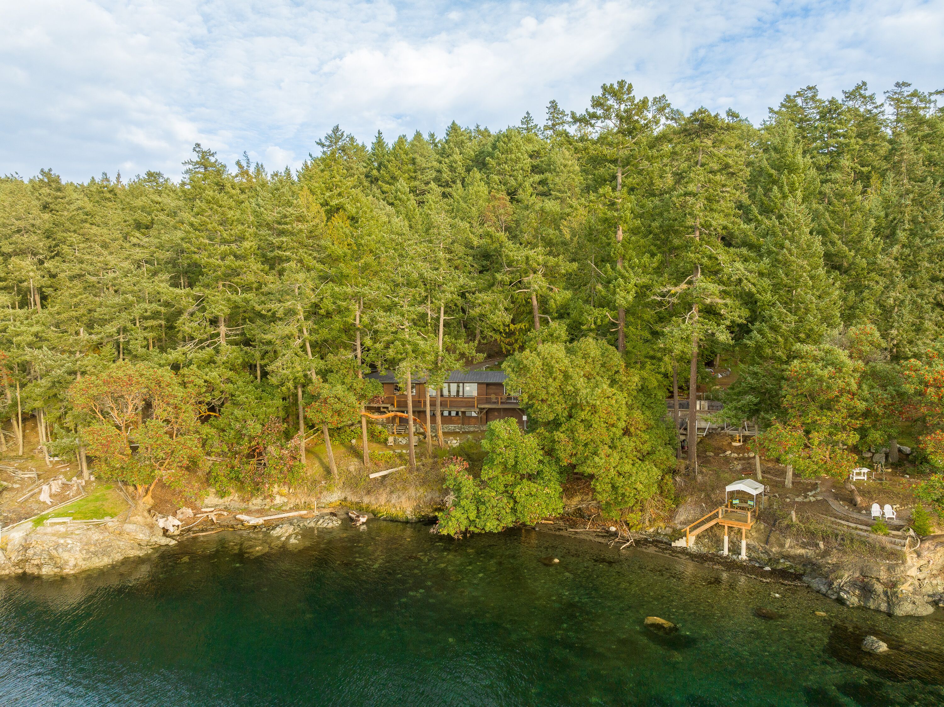 A secluded cabin surrounded by dense forest and a clear lake.