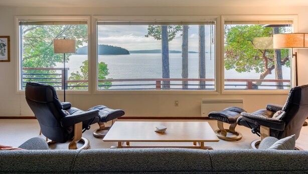 Une pièce avec vue sur un lac, deux fauteuils inclinables, une petite table et une lampe.
