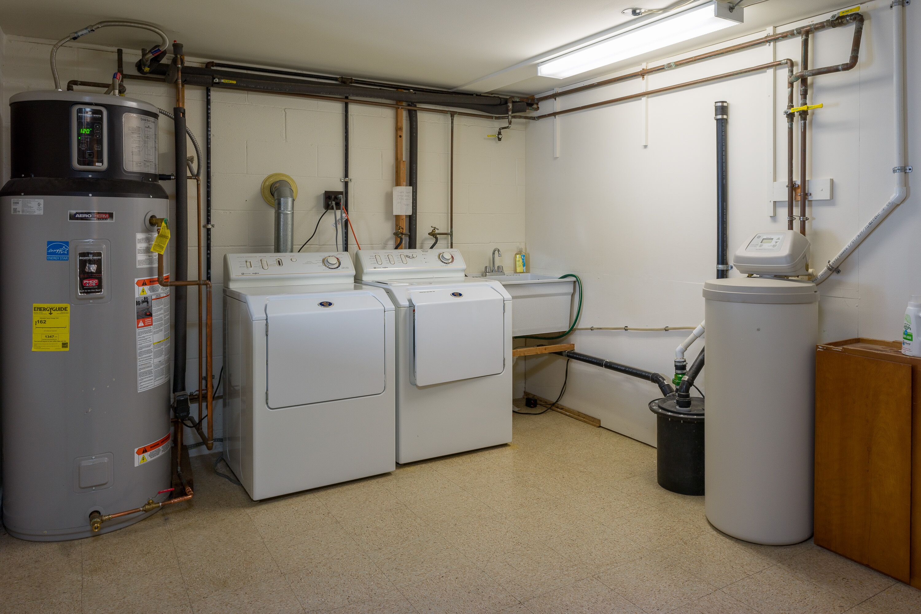 Un cuarto de lavado con calentador de agua, dos lavadoras y un sistema de filtración de agua.