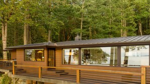 Une cabane dotée d’une terrasse, de rampes en bois et de fondations en pierre.